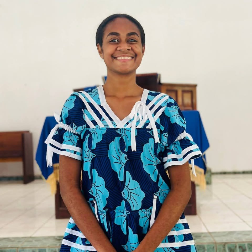 A young woman in island dress standing at the front of the church during worship